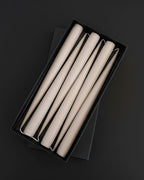 Set of six PLAMYA taper candles in Sand Ash (grey) shade arranged in a black box on a dark background