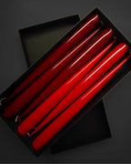 Set of red and burgundy taper candles in a black box on a dark background
