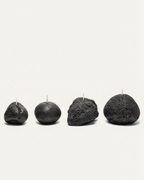 Four volcanic stone candles with textured surfaces arranged on a white background
