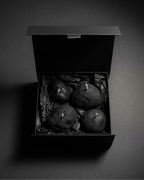 Set of four volcanic stone candles arranged in a black gift box on a dark background